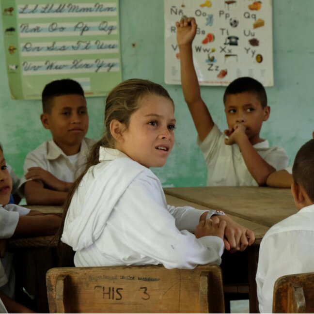 Studenten leren samen in een levendige klasomgeving, wat samenwerking en communicatieve vaardigheden bevordert.