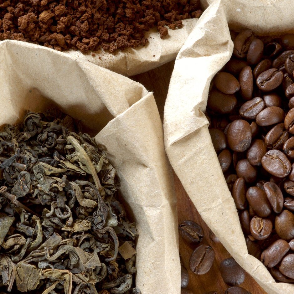 Výber čajových lístkov, mletej kávy a celých kávových zŕn v papierových vrecúškach, ktoré predstavujú obľúbené prísady do horúcich nápojov.