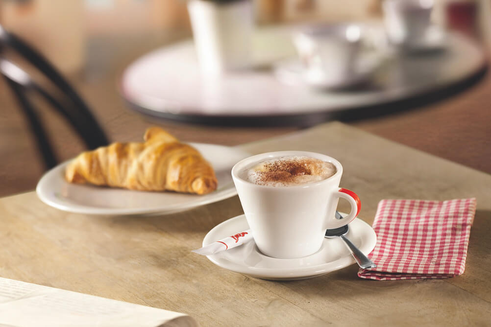Brosio - Kaffee in weißer Tasse mit Logo und Croissant
