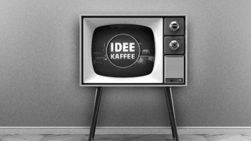 Retro televisie met het logo van Idee Kaffee tegen een minimalistische grijze muur. Perfect voor koffieliefhebbers.