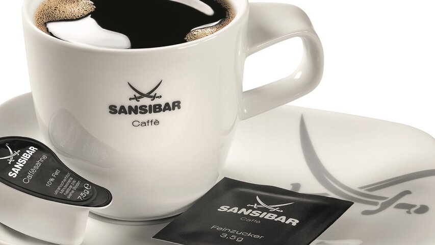 Black coffee in a stylish Sansibar mug, accompanied by cream and sugar for a perfect coffee experience.