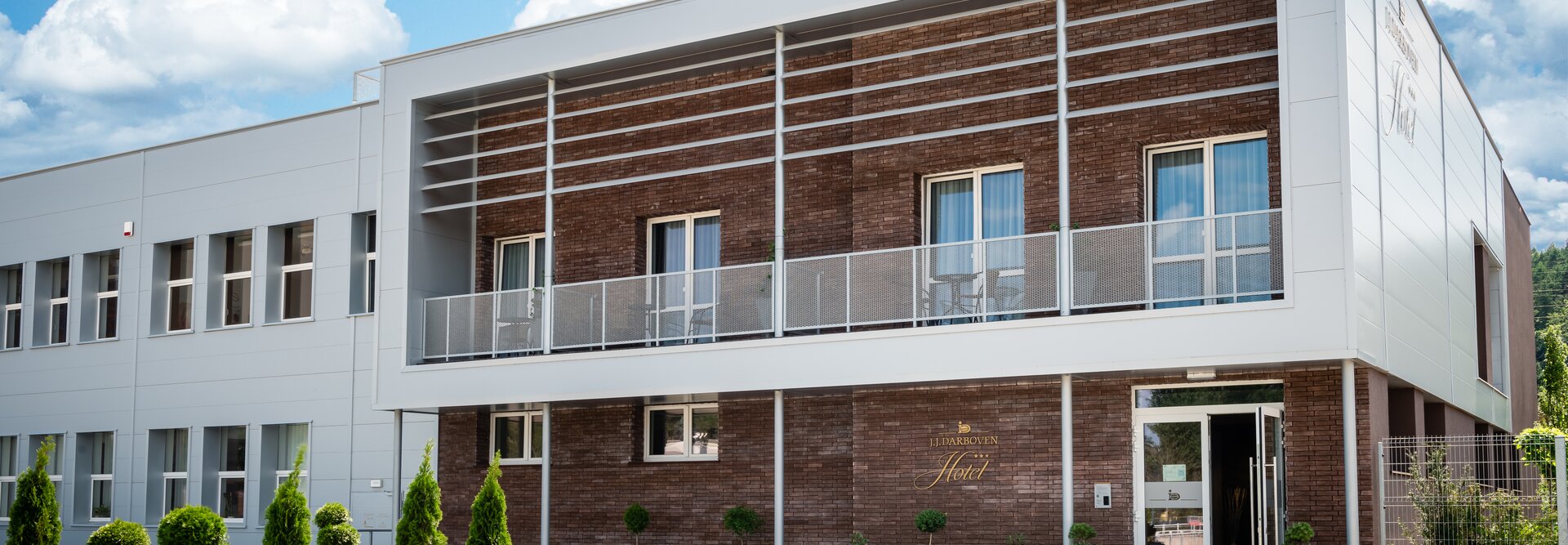 Nowoczesna fasada hotelu J.J. Darboven ze stylową architekturą i zagospodarowanym wejściem. Idealny na przytulne pobyty.