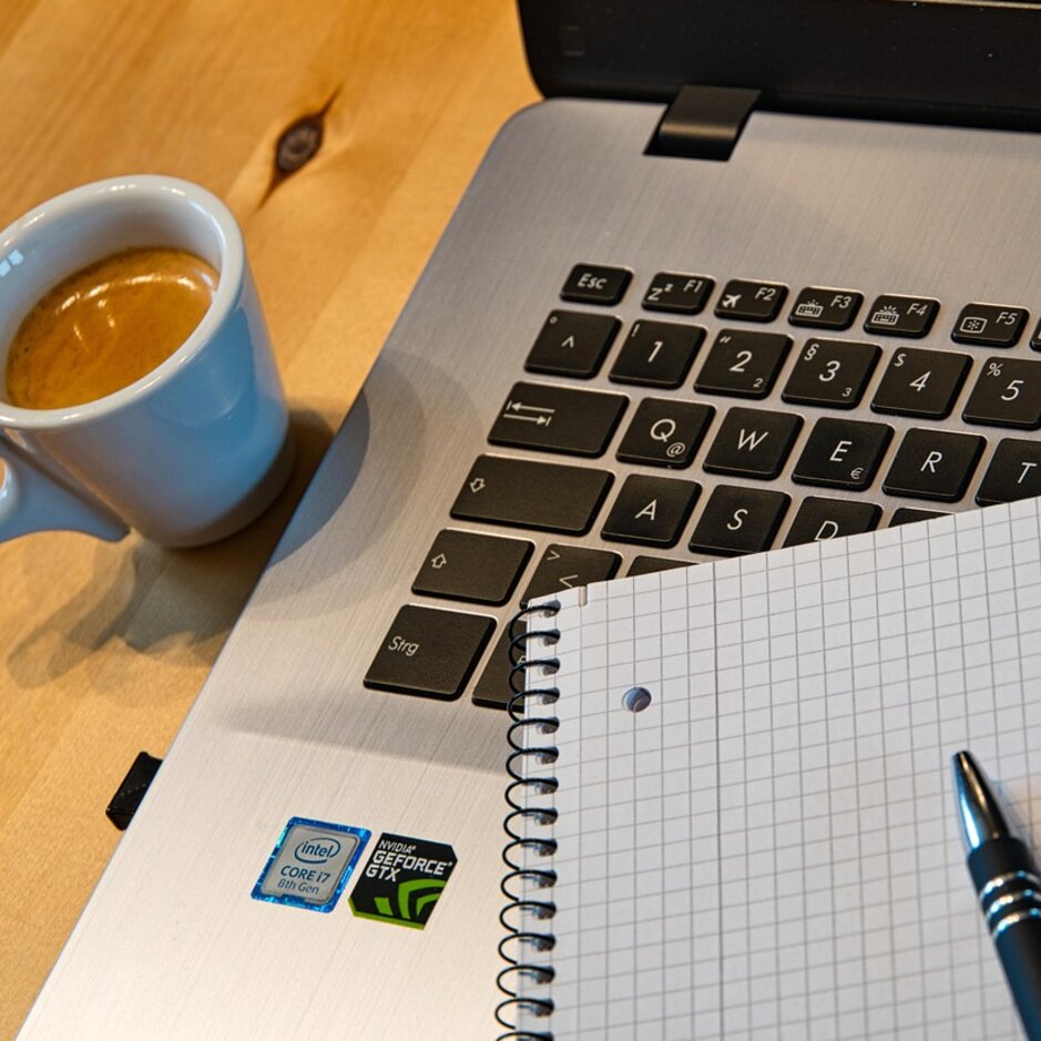 Laptop, notebook i filiżanka kawy ustawione na drewnianym biurku, idealne do produktywnego domowego biura.