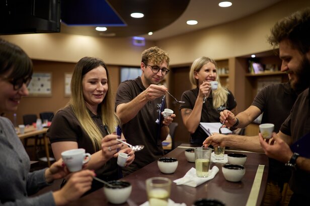 Uczestnicy cieszą się sesją degustacji kawy, próbując napojów i omawiając smaki w przyjaznej atmosferze kawiarni.